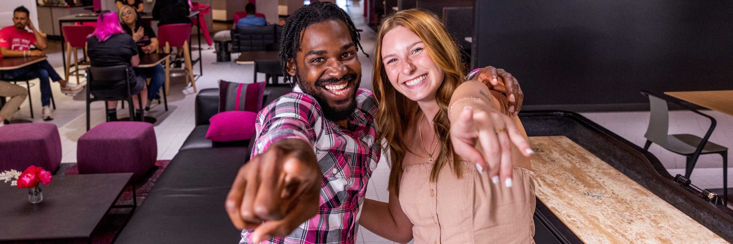 Two T-Mobile Employees smiling and pointing at the camera