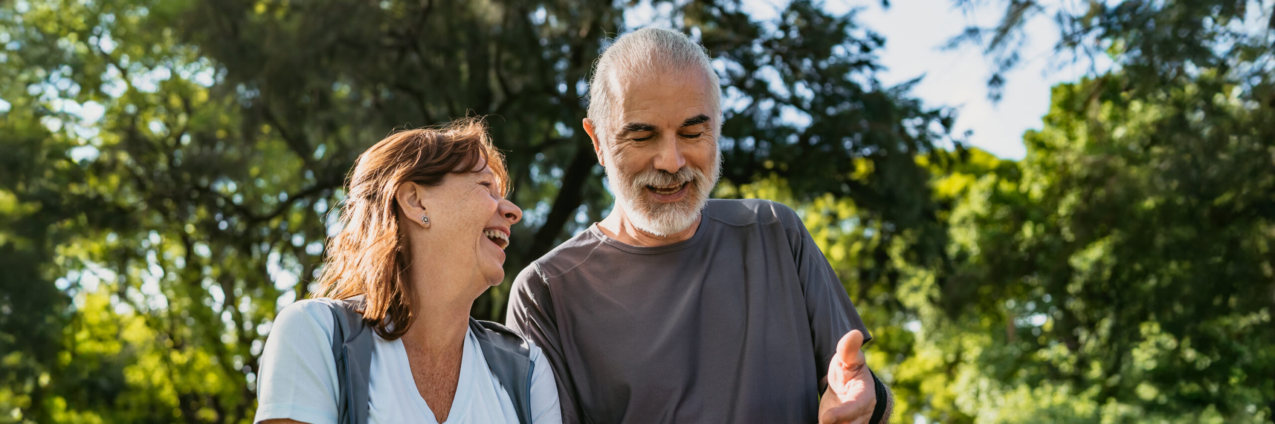 Two people walking and laughing in a park.